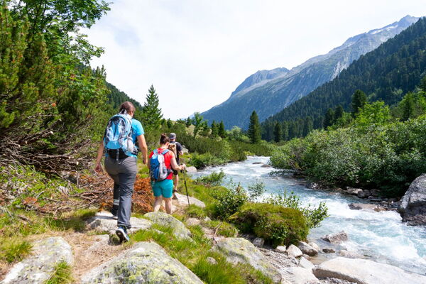 Familie beim Wandern entlang eines Bergbachs im Zillertal